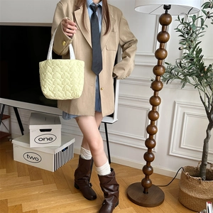 Quilted heart pattern handbag in pale yellow shown in a cozy indoor lifestyle setting