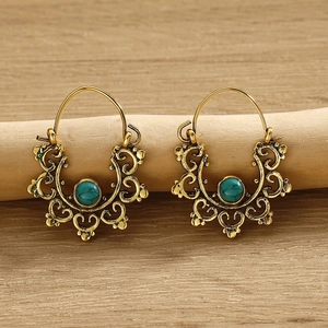 Bohemian gold hollow filigree hoop earrings with turquoise stones on wooden branch