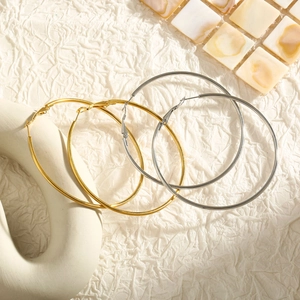Detailed comparison of minimalist gold and silver hoop earrings on a textured backdrop