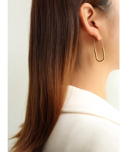 Detail of 18K gold plated long U-shaped earrings worn by a model in soft lighting