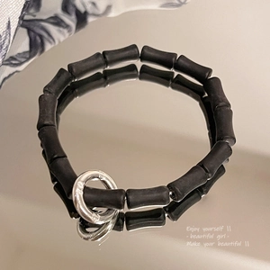 Close-up of black matte cylindrical beads with a polished silver metal ring buckle