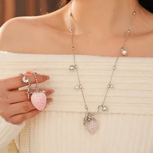 Pink resin strawberry pendant necklace with silver beaded chain for women on white sweater