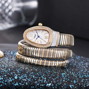 Detail of snake-shaped gold and silver watch band with crystal accents on a blue base