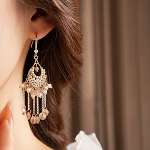 Close-up of bohemian tassel earrings with rhinestones and pearls on a female model