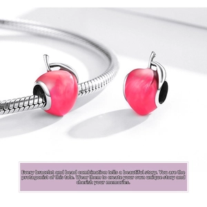 Macro detail of 925 silver pink enamel apple charm on a snake chain bracelet
