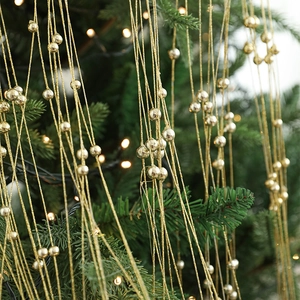 Guirlande de perles dorées sur sapin de Noël avec lumières blanches chaudes de fête
