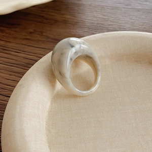Détail macro de la bague en résine marbrée crème avec texture lisse et motif veiné gris