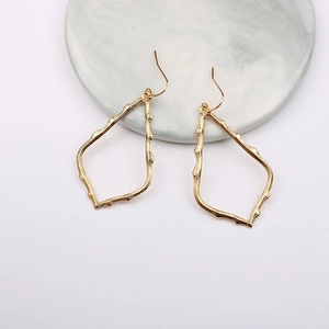 Golden irregular hollow teardrop earrings on marble display with minimalist modern design