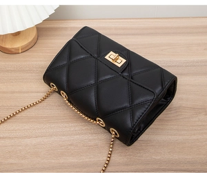Top view of a black quilted PU leather shoulder bag with gold chain strap on a wooden table