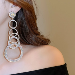 Close-up of model wearing large silver layered hoop earrings with sparkling rhinestones