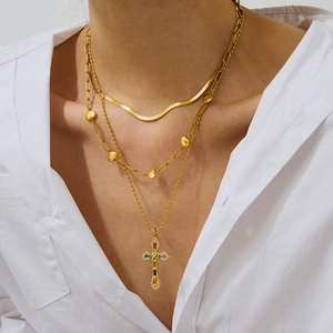 Mehrlagige goldene Kreuzkette mit Edelsteinen und Herzanhänger an einem Model
