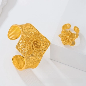 Detailed view of hollow floral lace bangle and 3D petal ring set in bright gold finish