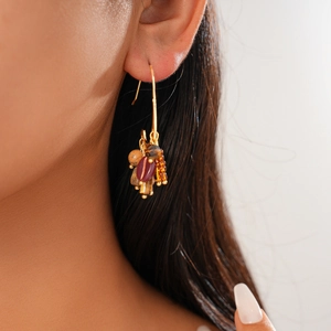 Gros plan de boucles d'oreilles bohèmes à pampilles dorées 18 carats et perles sur un mannequin