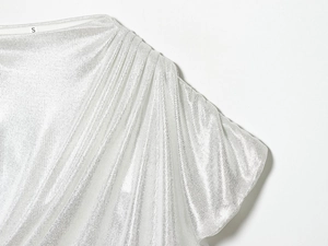 Détail du tissu en maille argentée à paillettes avec des plis élégants sur l'épaule