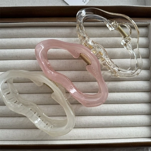 Close-up of three cloud-shaped hair claws in transparent, pink, and beige on velvet lining