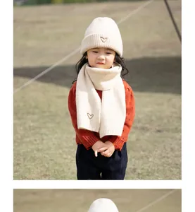 Close-up of cream knit hat and scarf set with gold heart embroidery for children