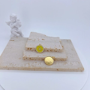 Detail of yellow enamel lemon slice pendants with golden textured back on stone base
