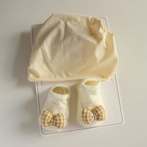 Detailed close-up of newborn baby soft cotton hat and matching bow socks set in light yellow