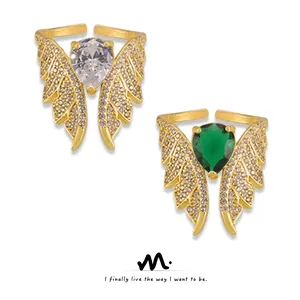 Detail of gold angel wing open rings with emerald and clear teardrop stones