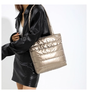 Detail showing metallic champagne gold puffer tote bag with quilted texture and wide strap