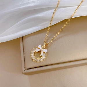 Close-up of gold chain necklace with sparkling zircon ring and white bow pendant details