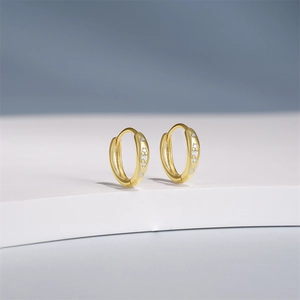 Detailed view of gold plated twist hoop earrings with sparkling cubic zirconia inlay