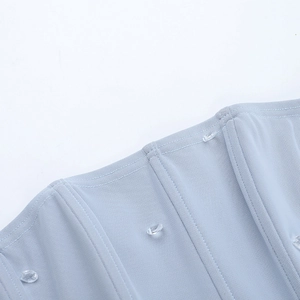 Détail du tissu en maille bleu clair avec strass étincelants et coutures verticales