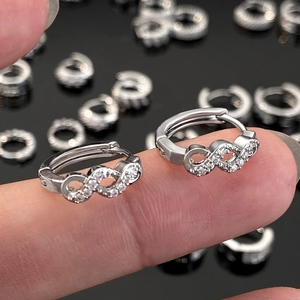 Detail shot of silver curved huggie earrings with micro-set zircons on a finger