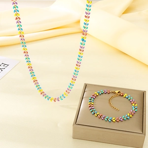 Detail view of colorful leaf-shaped enamel necklace and bracelet set on a silk backdrop