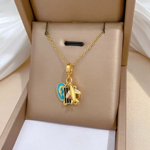 Chic gold titanium necklace with plane, suitcase, and heart pendants in a gift box