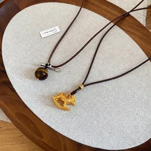 Tiger eye bead and golden rocking horse pendant necklace set on an aesthetic wooden tray