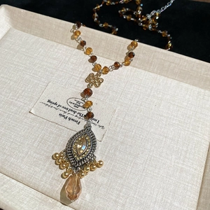 Detail of vintage beaded necklace with oval crystal pendant and amber drop on fabric