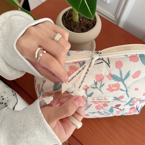 Detail of quilted floral makeup bag with pink tulips and decorative zipper strap