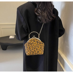 Detail of leopard print shell bag with metal top handle and gold chain strap shown on model