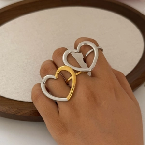 Minimalist hollow heart shaped stainless steel rings in silver and gold on a model hand
