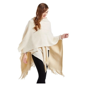 Elegante scialle in maglia beige con nappe mostrato su una modella in uno studio fotografico