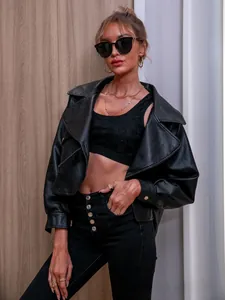 Détail d'une veste courte en similicuir noir avec haut en dentelle et jean