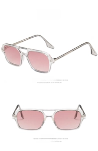 Detail view of pink gradient lenses and clear white aviator frame with double bridge