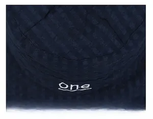 Gros plan d'un chapeau bob bleu marine montrant la texture quadrillée et le logo One brodé