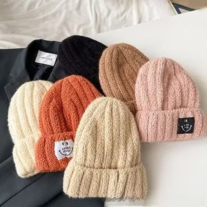 Detailed shot of multi-color ribbed knit beanies with smile patches in cozy wool