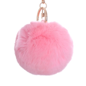 Soft pink fluffy pompom keychain with golden metal clasp on minimalist white background