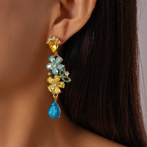 Close-up of floral drop earrings with blue and yellow crystals on a model's ear