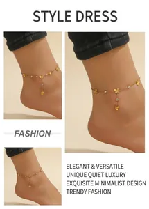 Détail de bracelets de cheville dorés avec breloques papillon et cœur sur une plage