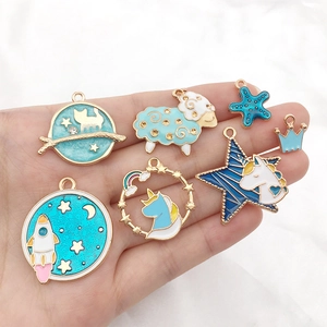 Assortimento di ciondoli in smalto blu unicorno e spazio su mano con dettagli in oro