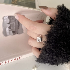 Dettaglio dell'anello in argento S925 geometrico con zircone indossato da una modella con libro