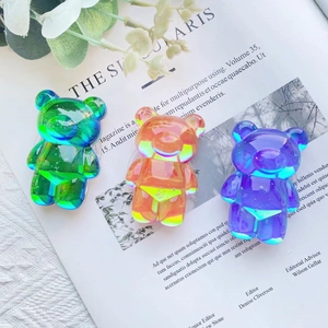 Three-piece set of iridescent bear-shaped phone grips on a magazine background