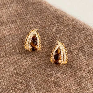Detail of half-hoop earrings with tiger eye beads and pavé zircons on knit fabric