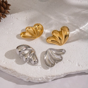 Polished butterfly wing stud earrings in gold and silver finish on stone background