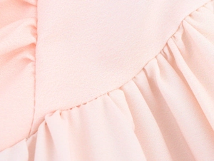 Dettaglio ravvicinato di pieghe in tessuto rosa e cuciture su un vestito vintage
