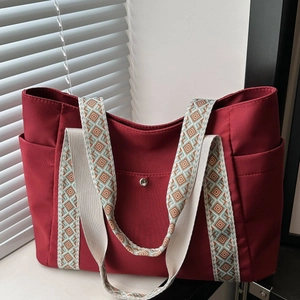 Dettaglio della borsa tote in tela rossa con tracolle geometriche e tasche laterali